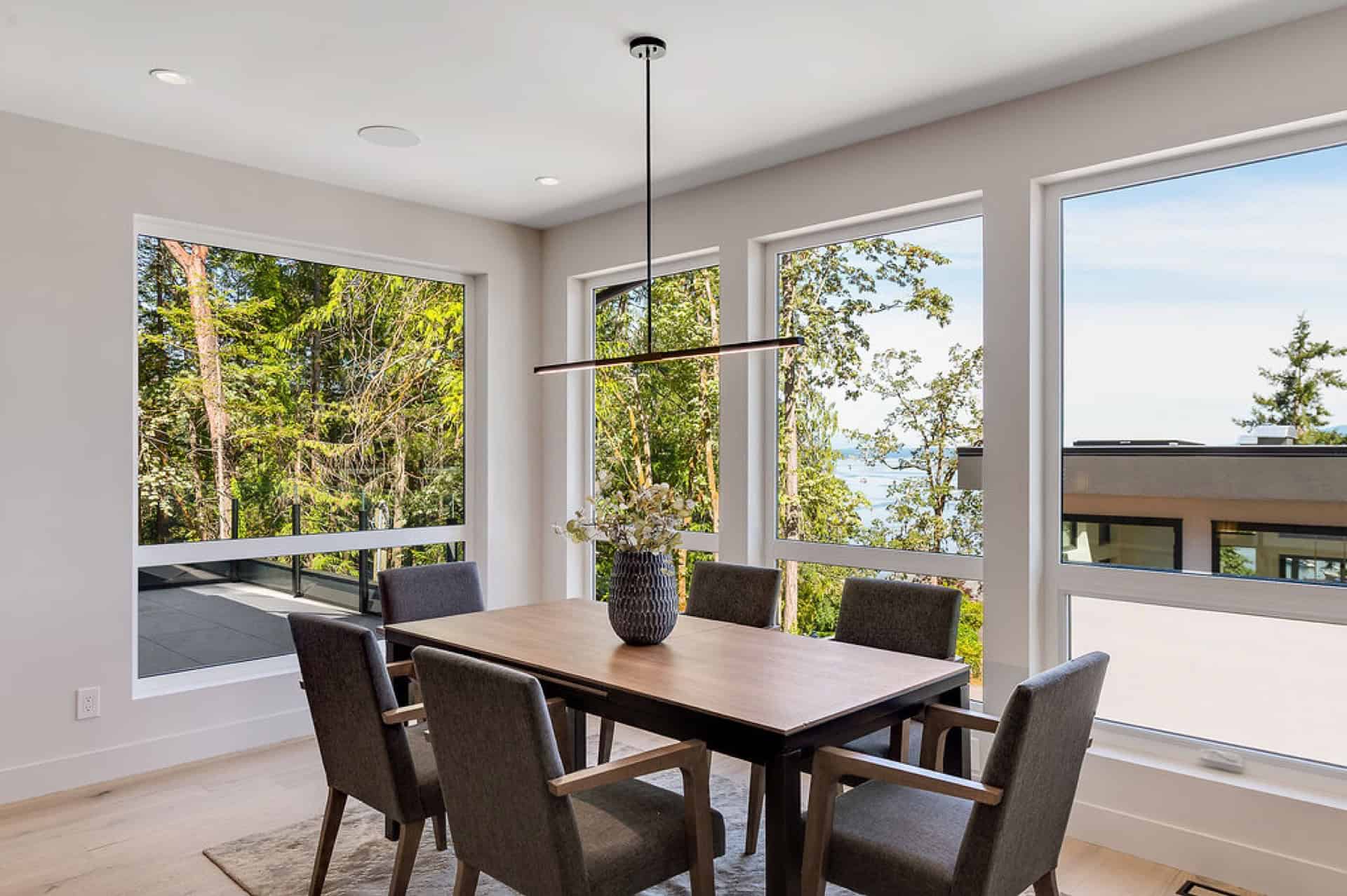 Elegant dining area by large picture windows with natural light, modern table and chairs.
