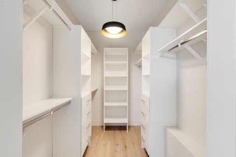Spacious white walk-in closet with organized shelving and hanging rods.