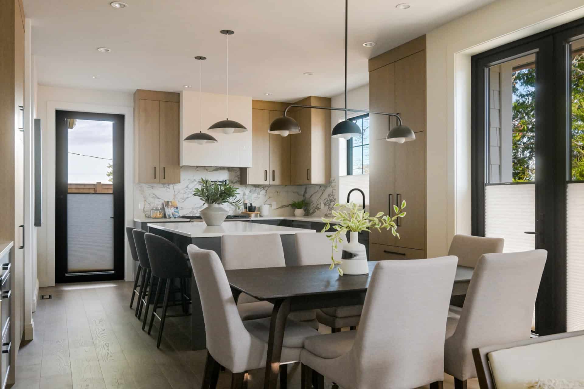 Modern kitchen with island, pendant lights, and dining area in Cedar & Stone project by White Wolf Homes.