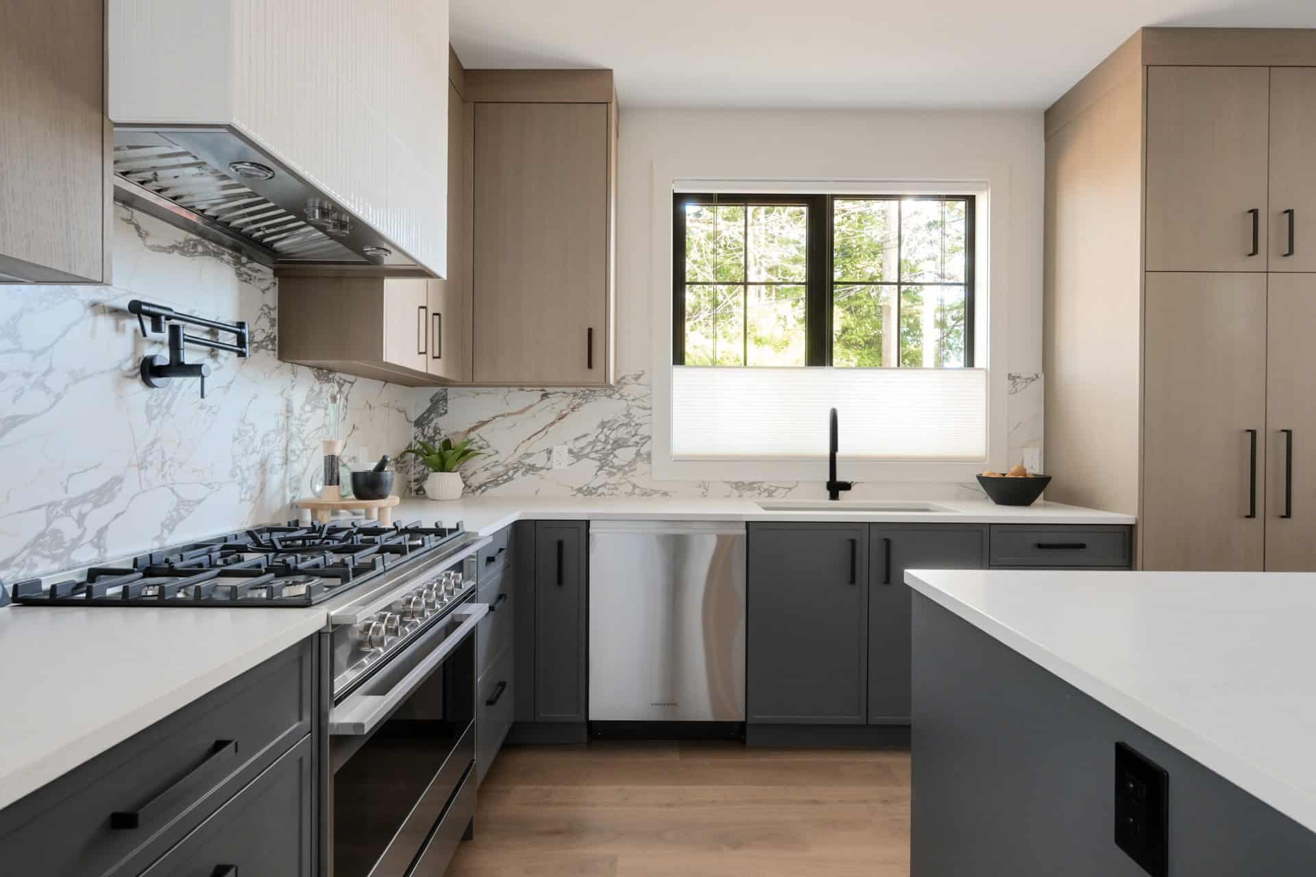 Modern kitchen by White Wolf Homes with marble backsplash, grey cabinetry, and a stainless steel range.
