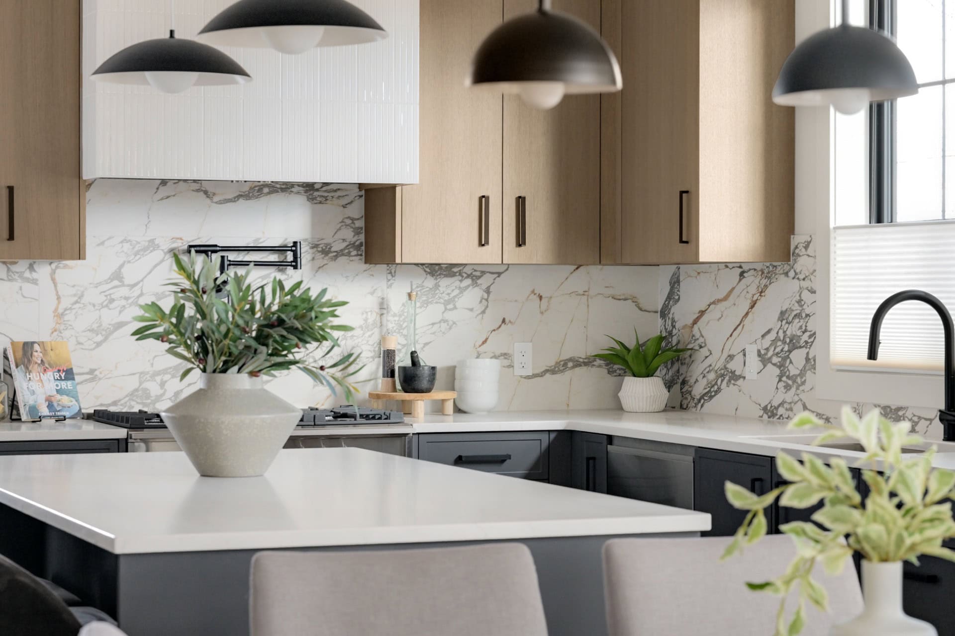 Modern kitchen by White Wolf Homes with marble backsplash, wood cabinets, and kitchen island.