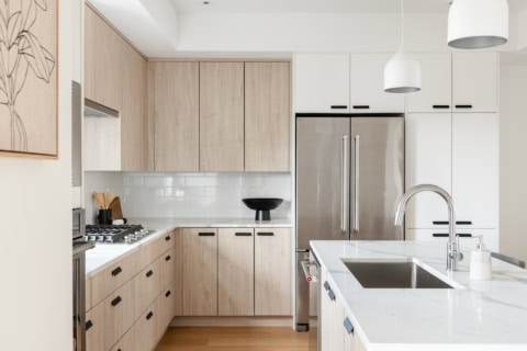 White Wolf Homes modern kitchen with light wood cabinets and stainless steel appliances in Victoria.