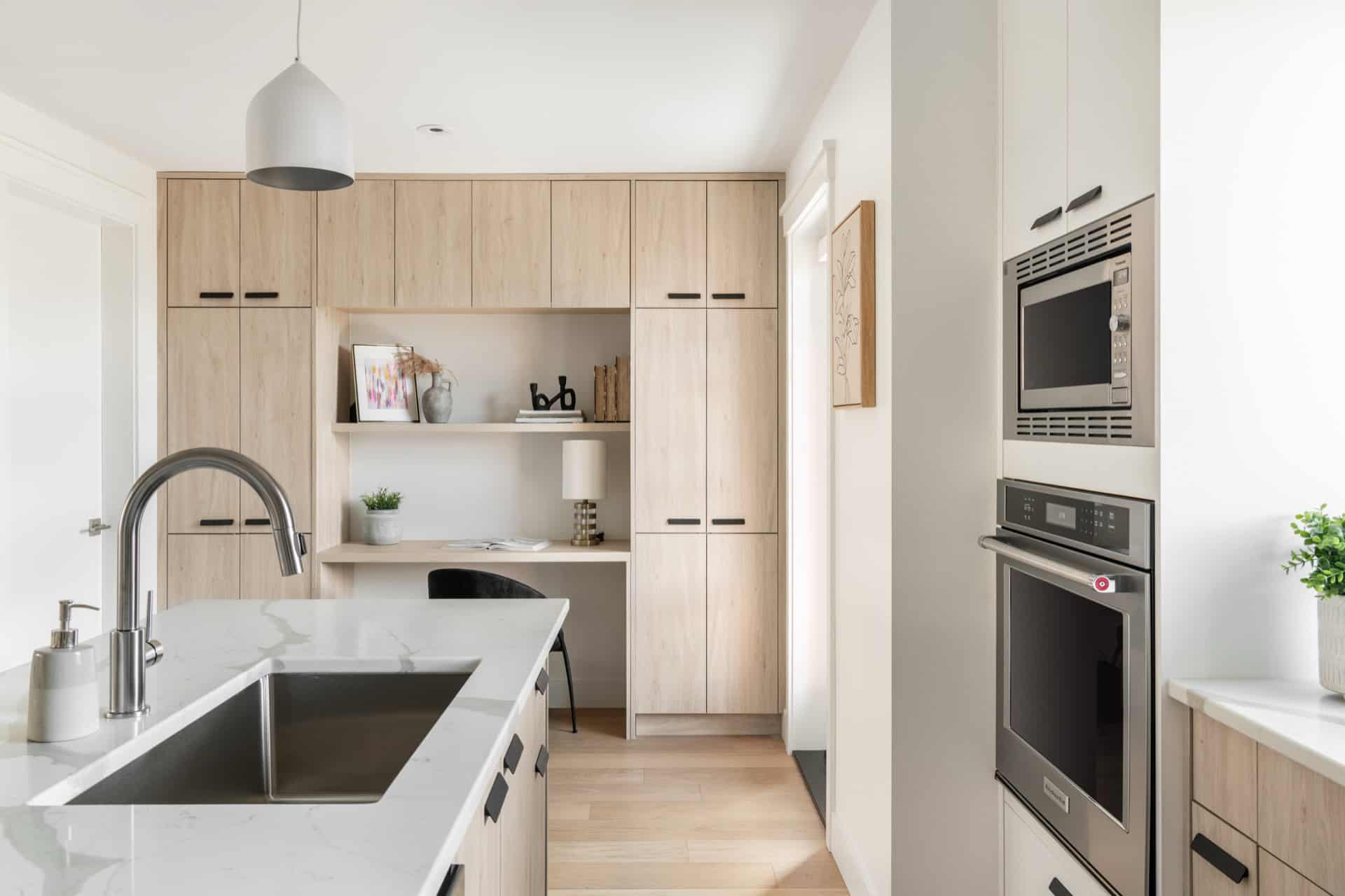 Modern kitchen with light wood cabinets, island sink, and stainless steel appliances.