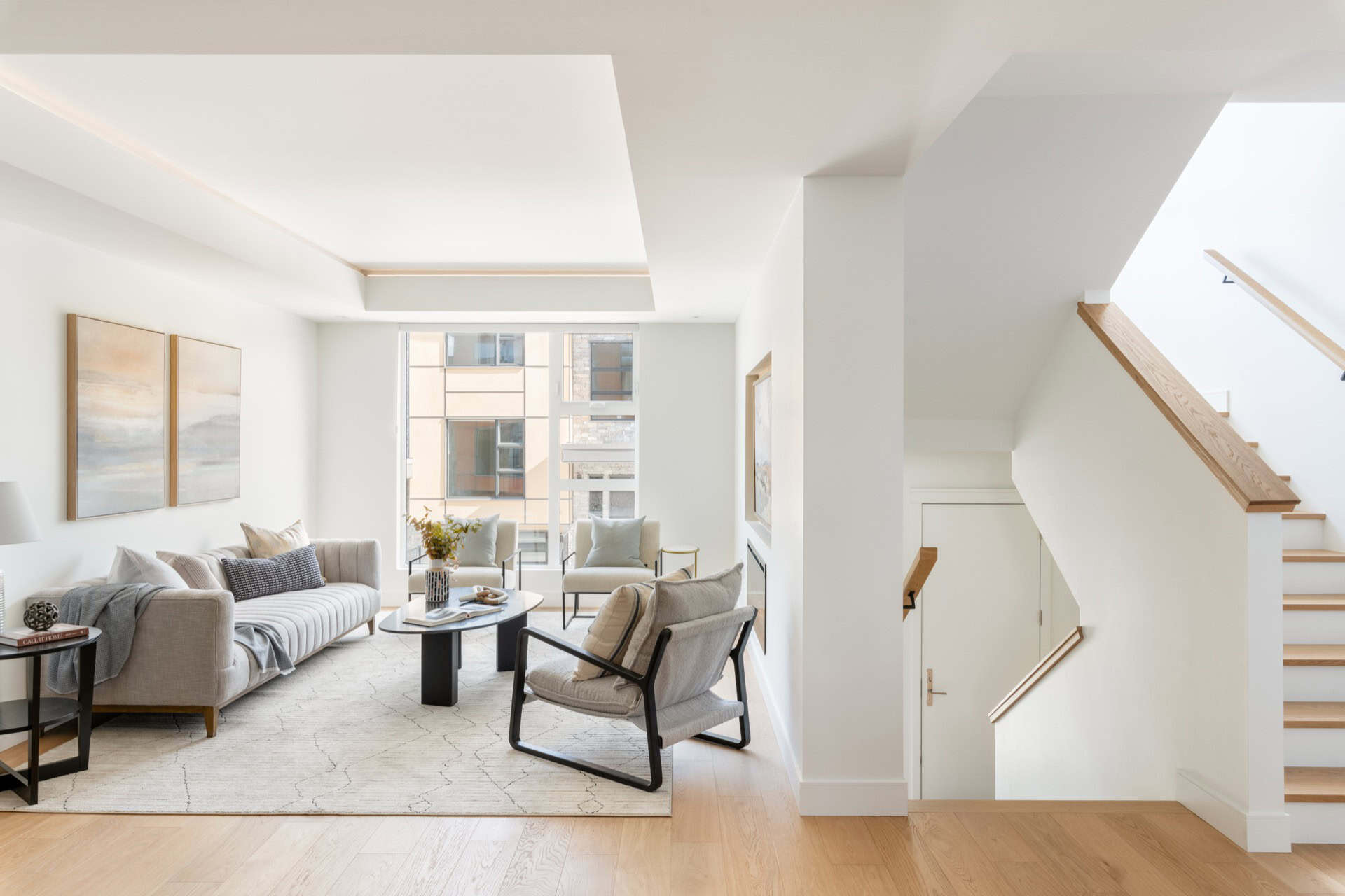 White Wolf Homes living room with modern seating and staircase, bright open-concept design.