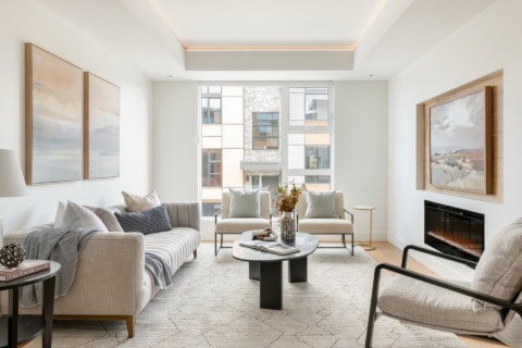 Living room with modern furniture, neutral tones, fireplace, large windows, and natural light.