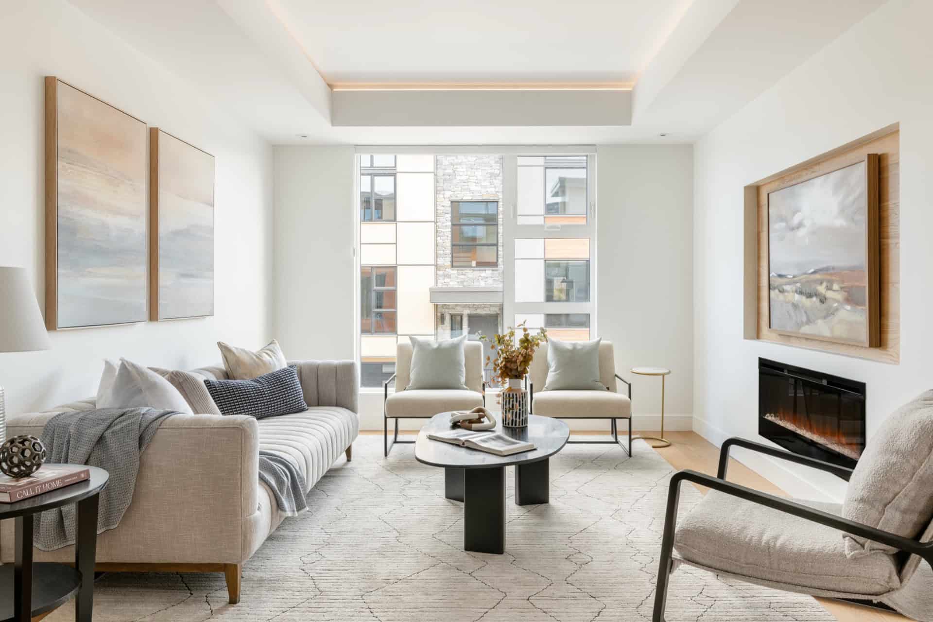 Living room with modern furniture, neutral tones, fireplace, large windows, and natural light.