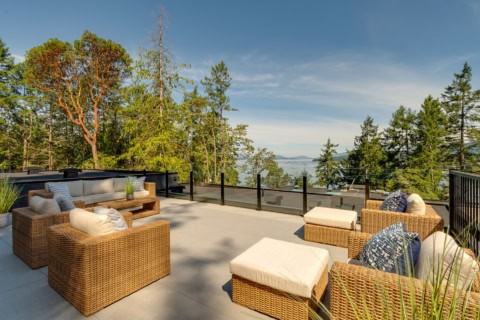 Outdoor seating on a canopy terrace with wicker furniture and ocean view.