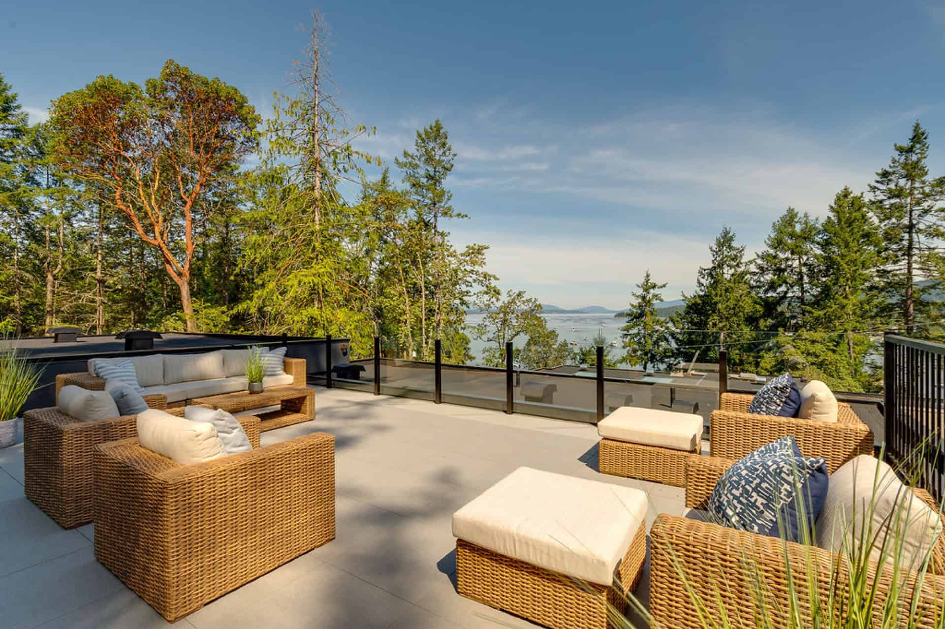 Outdoor seating on a canopy terrace with wicker furniture and ocean view.