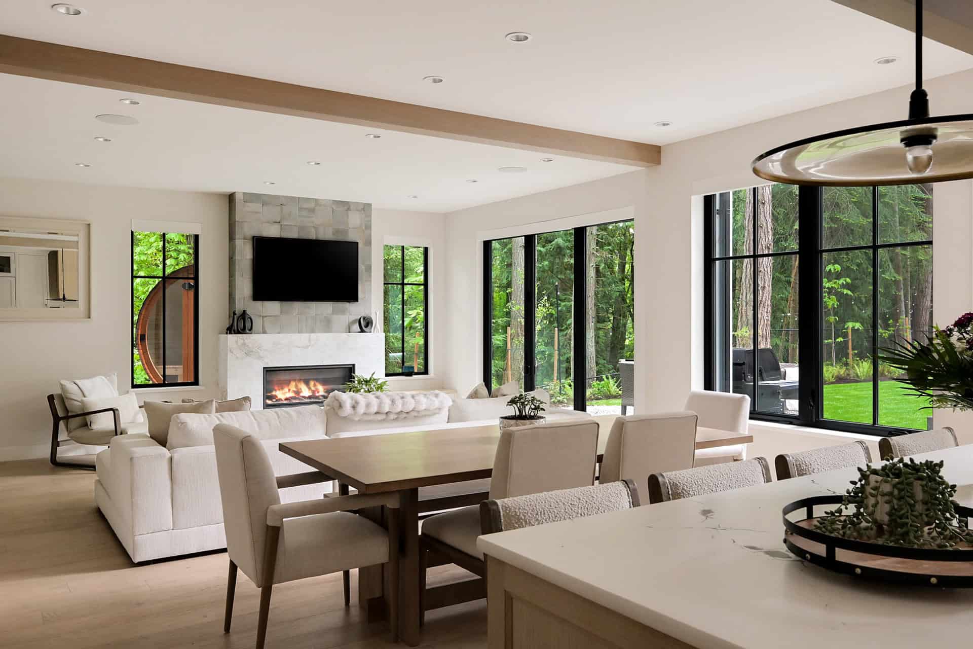 Bright open-plan living and dining area with large windows, fireplace, and neutral furnishings.