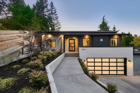 Grey and black modern duplex style home with landscaped path to entrance and a two-car garage.