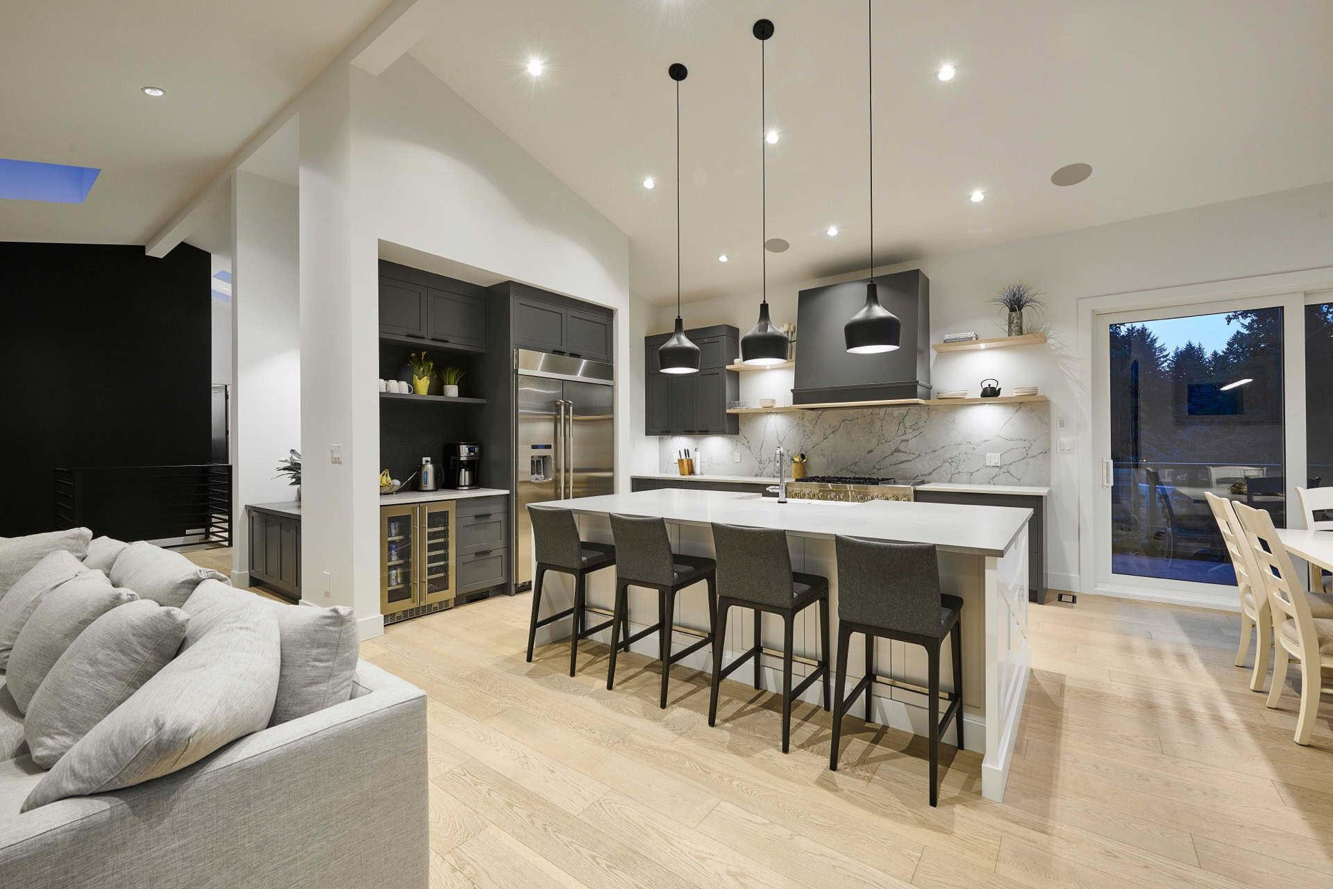 Modern open-concept kitchen in a white-walled home with island and black pendant lights.