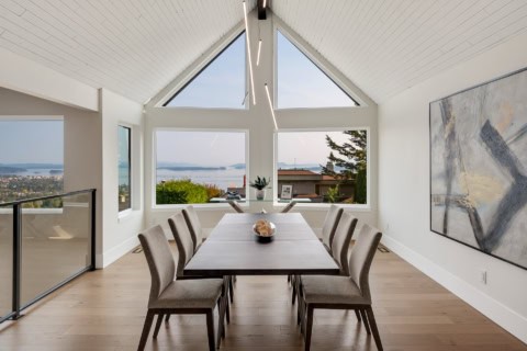Modern dining room with large triangular windows and ocean view in Victoria BC.