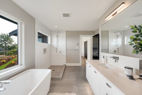 Bright modern bathroom with freestanding tub, double vanity, and large window.