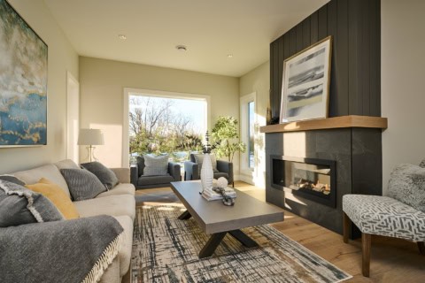 Bright living room with modern fireplace, neutral furnishings and large windows.
