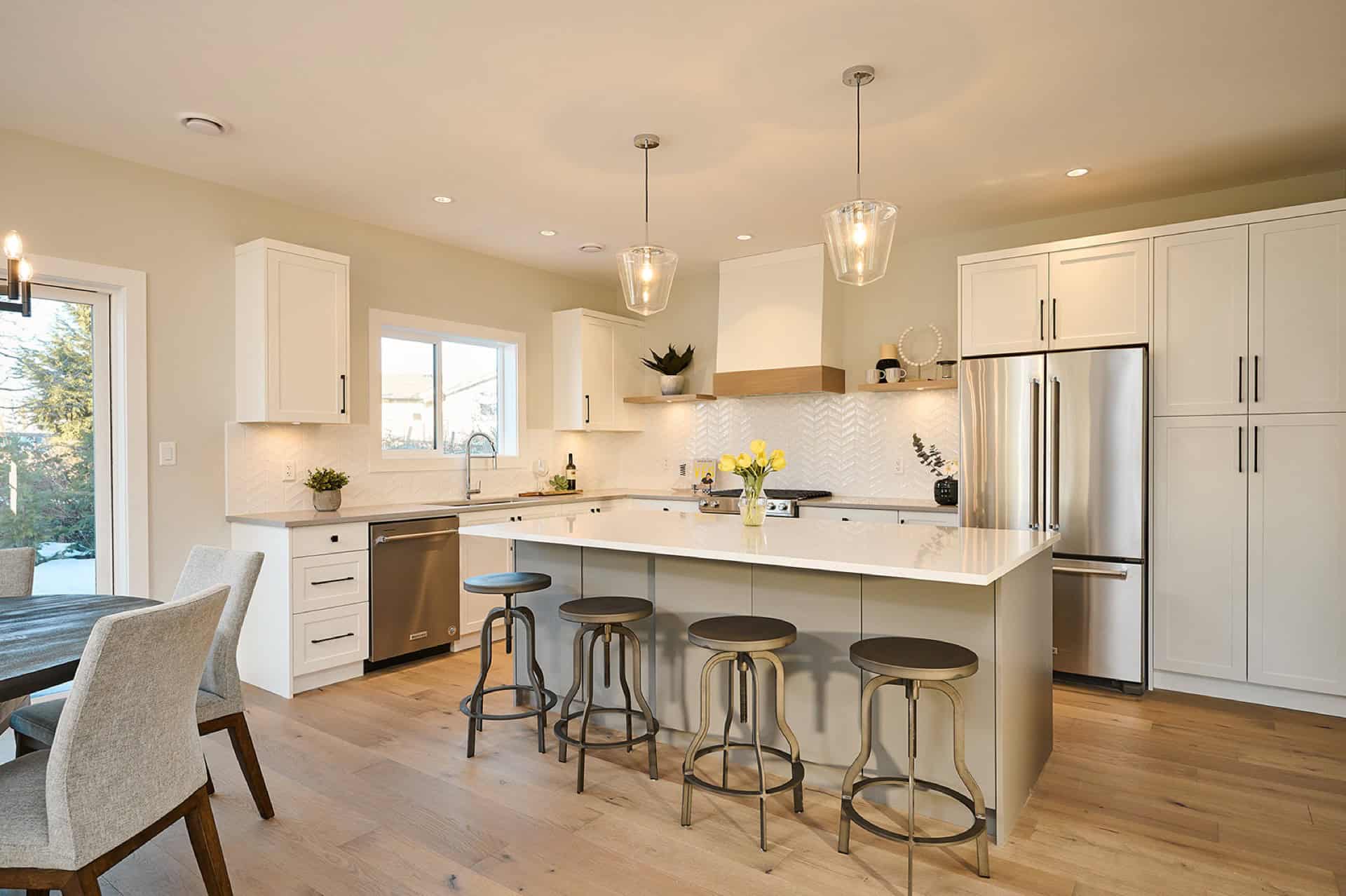 Modern white kitchen with island, pendant lights, and stainless appliances in Meadowview home by White Wolf Homes.