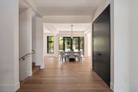 Bright open-plan dining area in a new Victoria BC home with large windows and hardwood floors.