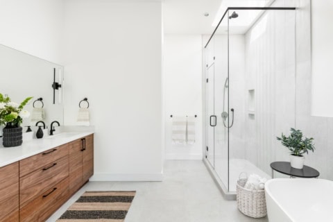 Modern bathroom with double vanity and glass shower in a bright Victoria home by White Wolf Homes.