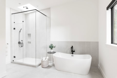 Modern white bathroom with freestanding tub and glass shower enclosure in Victoria BC.