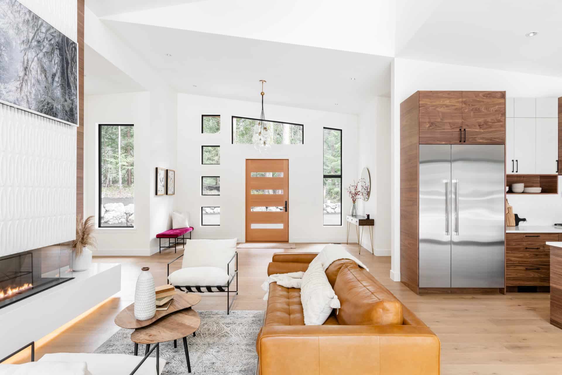 Modern open-concept living room with caramel leather sofa and contemporary kitchen in Victoria BC.