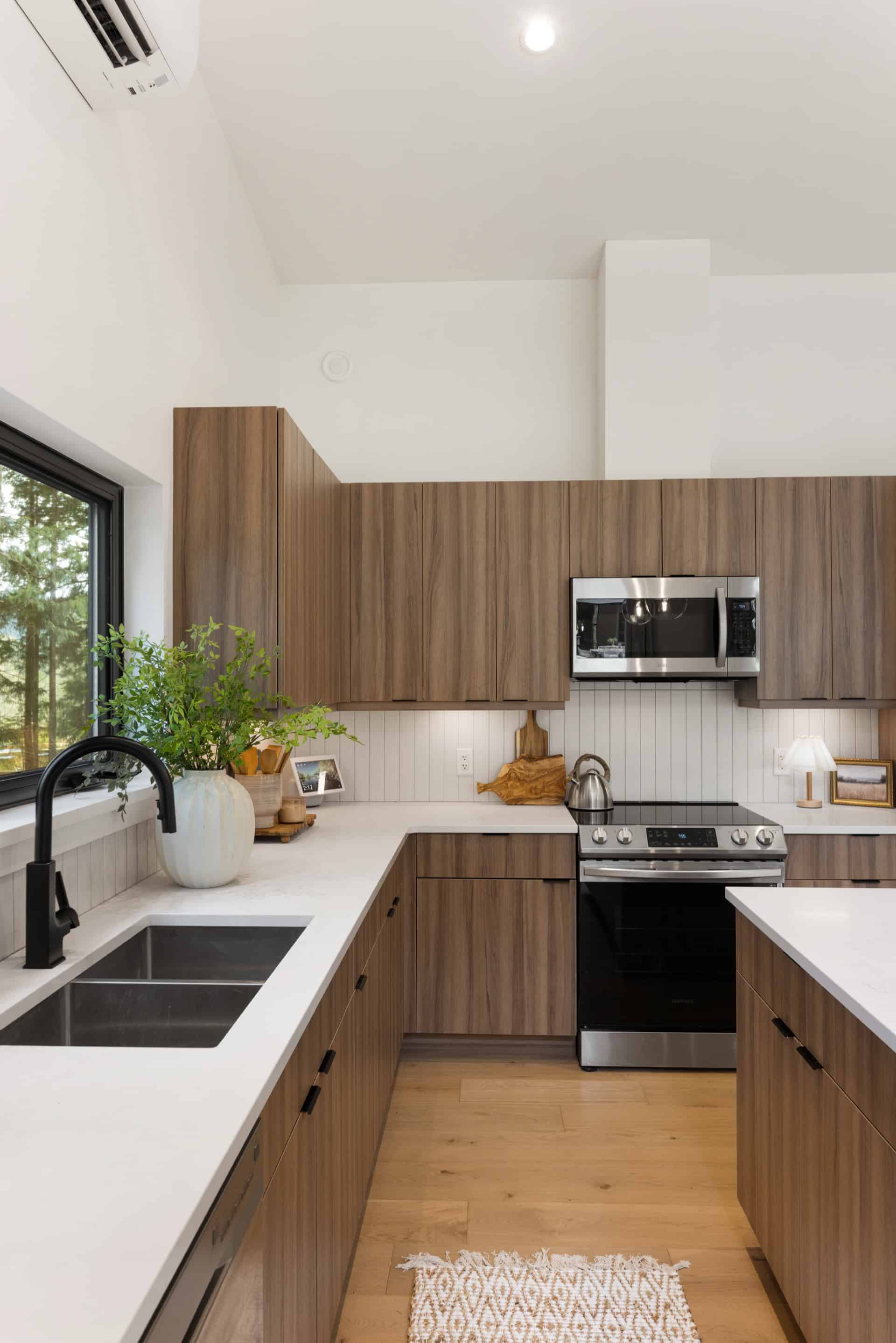Modern kitchen with wood veneer cabinetry, white countertops, and stainless steel appliances in Woodside.