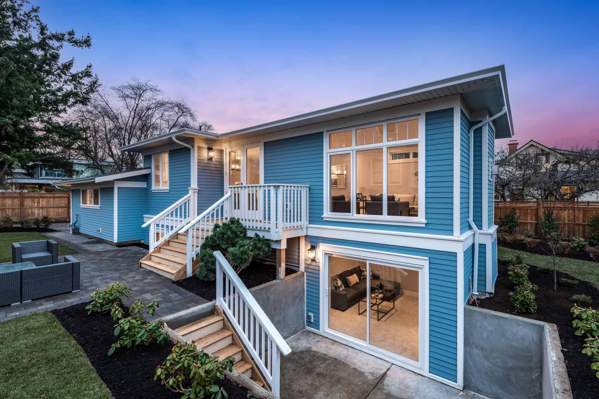 Blue modern two-story custom home in Victoria BC by White Wolf Homes with blue siding and large bay windows.