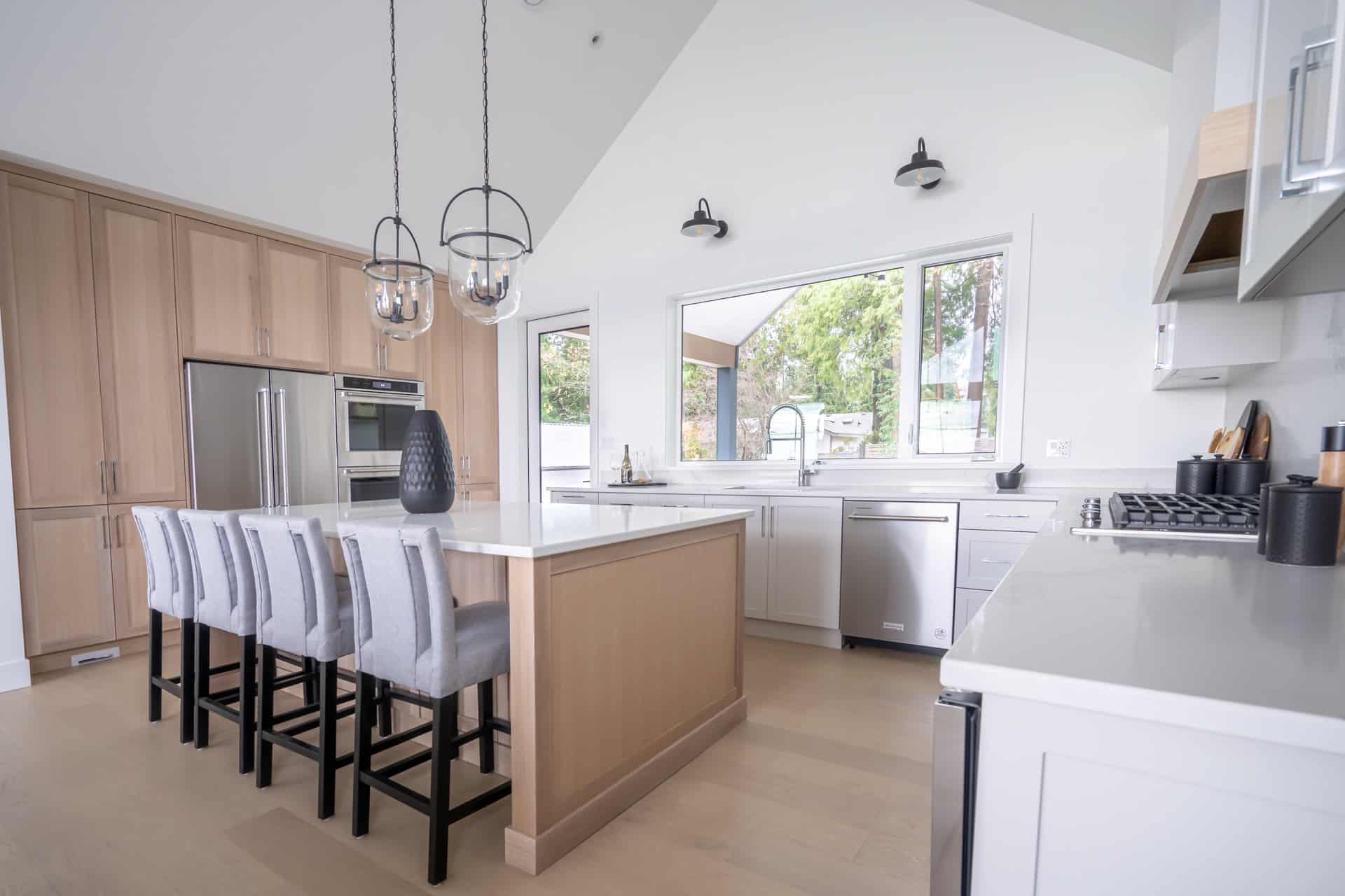 Modern kitchen by White Wolf Homes in Victoria BC with island, stainless appliances, and white cabinets.