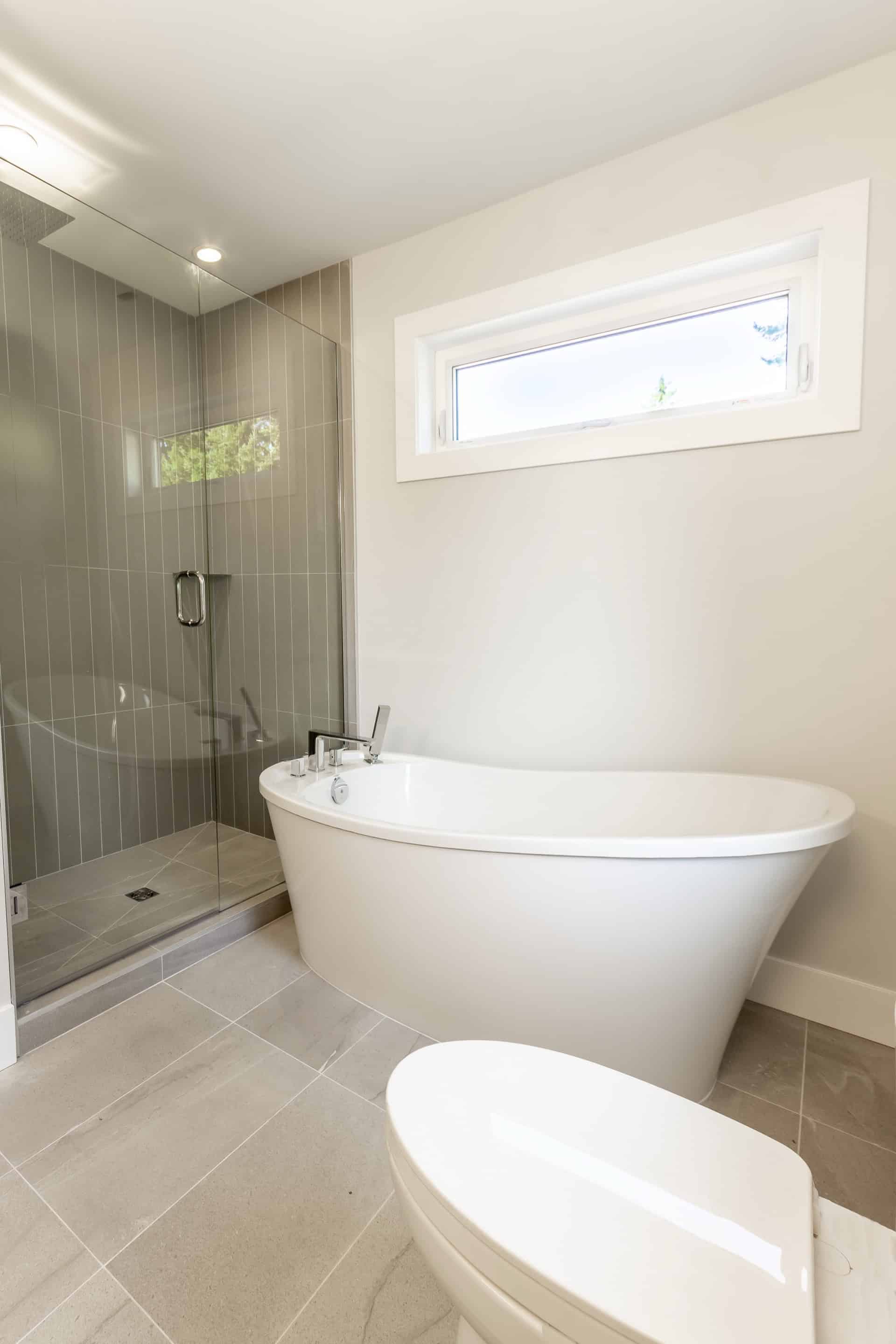 Modern bathroom with freestanding tub and glass shower in a Victoria BC home.