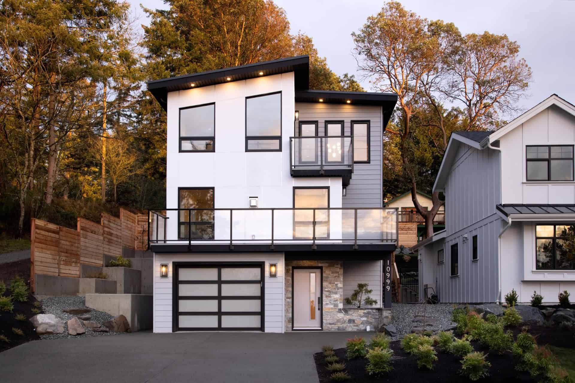 Modern two-story white home with large windows and black accents by Victoria BC builder.