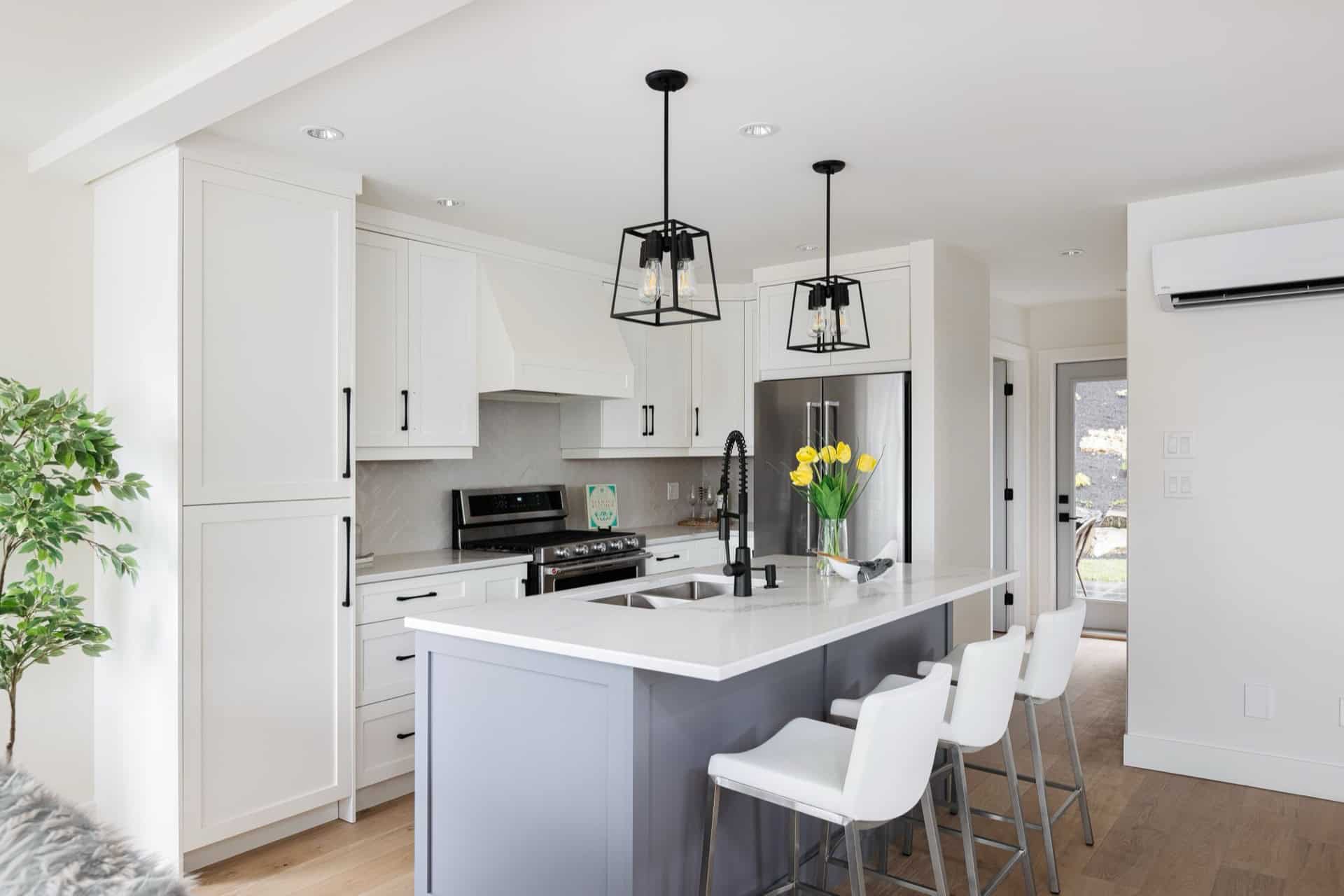 Modern white kitchen with island, pendant lights, and bar seating in Victoria BC home.