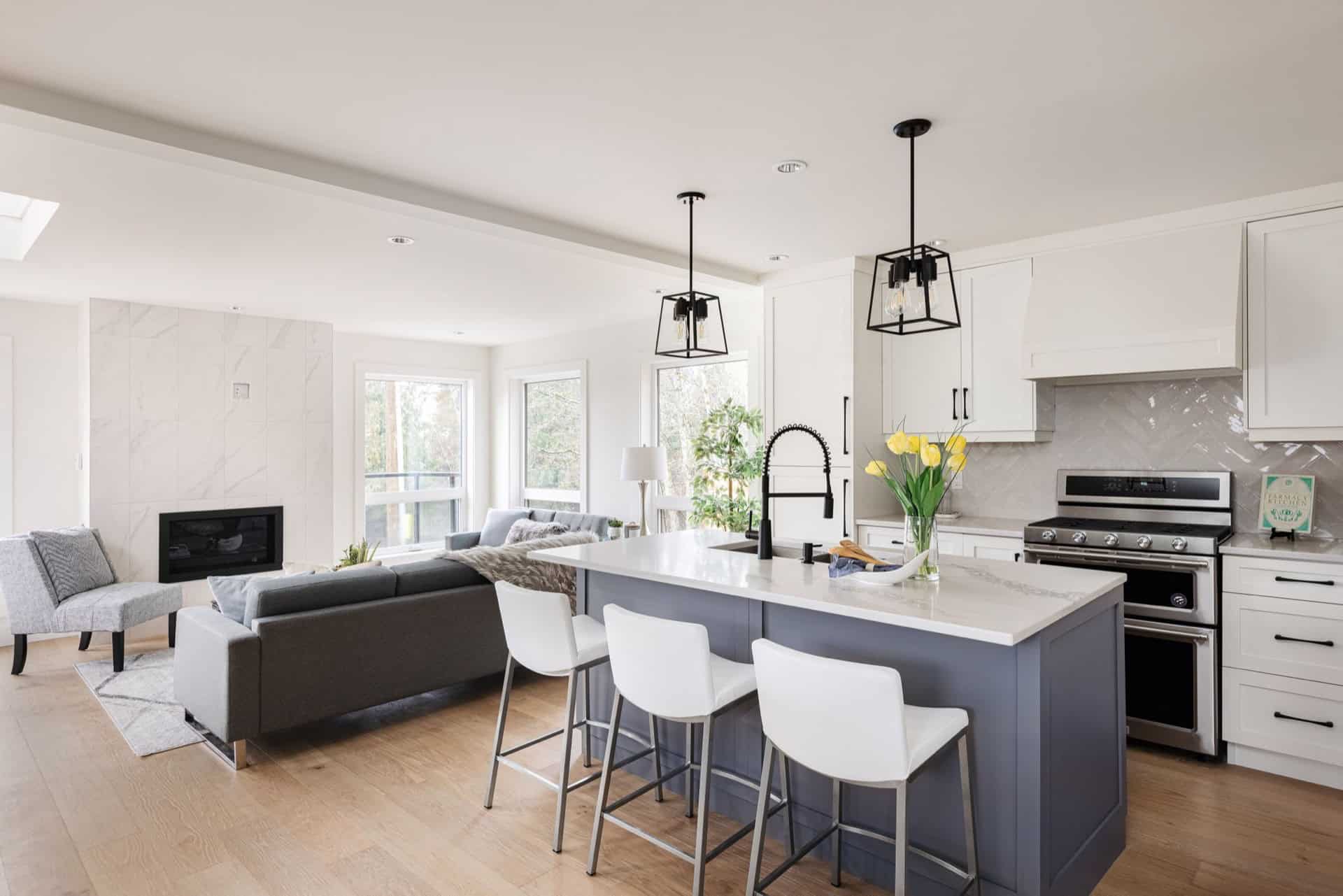 Open-plan kitchen with large island, white cabinets, stainless steel appliances and pendant lights.