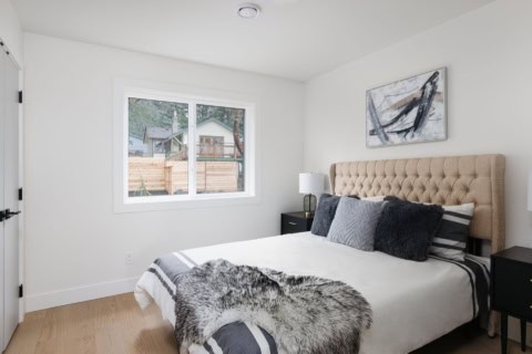Bright bedroom with window view, beige upholstered bed, and modern decor.