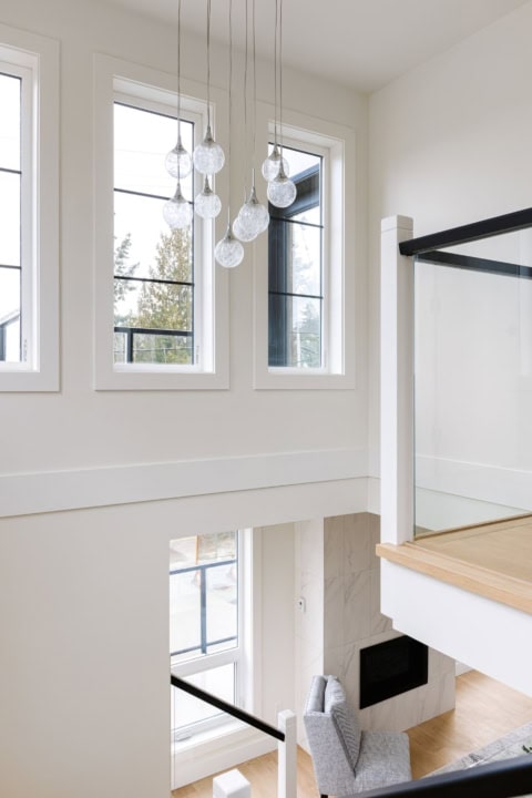 Bright, airy interior with large windows, chandelier, and modern staircase at Arbutus Rise by White Wolf Homes.