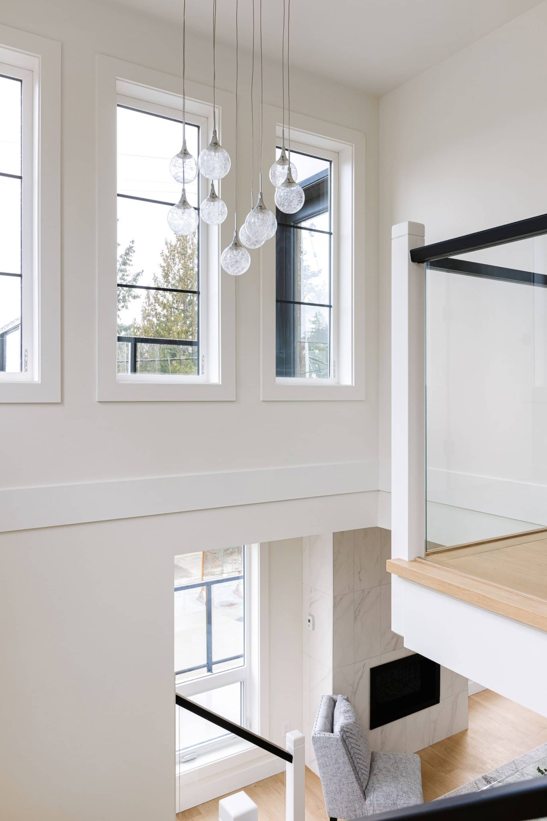 Bright, airy interior with large windows, chandelier, and modern staircase at Arbutus Rise by White Wolf Homes.