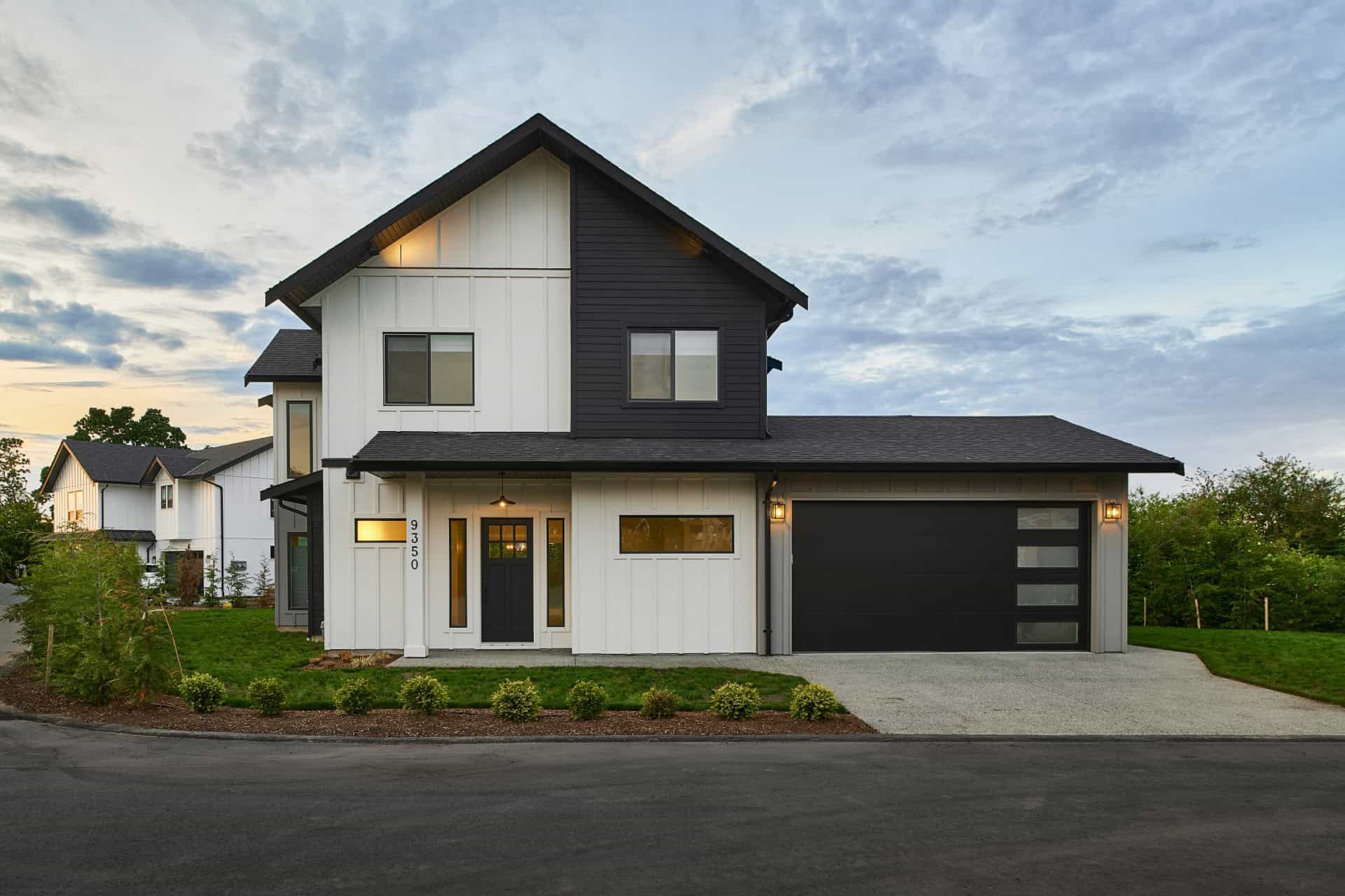 Modern two-story home with white and dark siding, attached garage, and landscaped front yard.