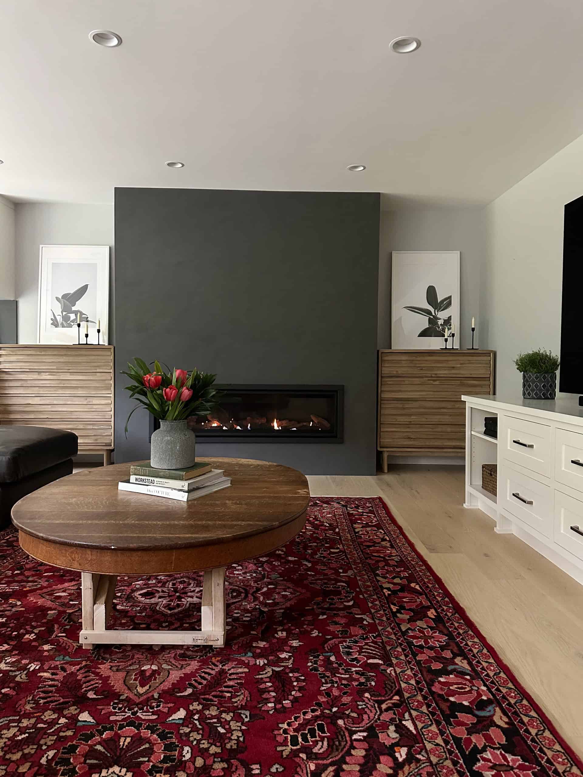 Modern living room with fireplace, dark accent wall, and wooden furnishings.