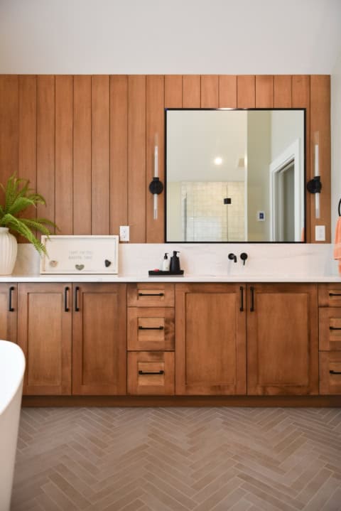 Modern bathroom vanity with wooden cabinetry and large mirror in Victoria BC home.