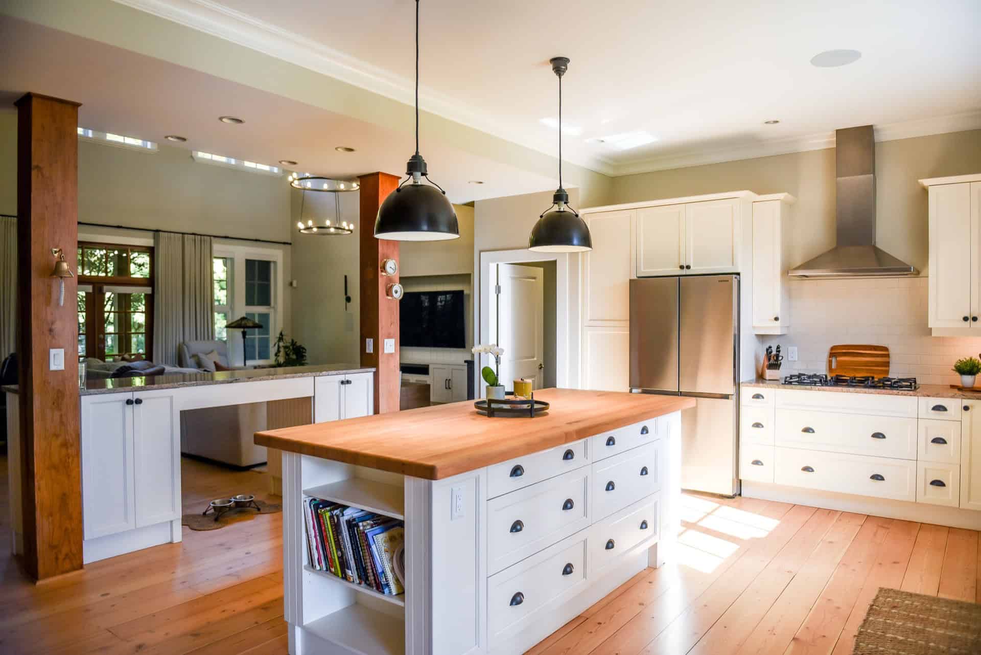 Bright modern kitchen with white cabinetry, central island, stainless steel appliances and natural wood accents.