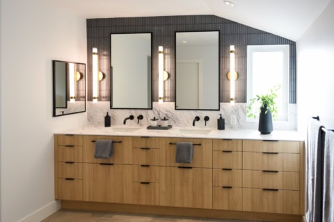 Bright modern bathroom vanity with double mirrors and black fixtures.