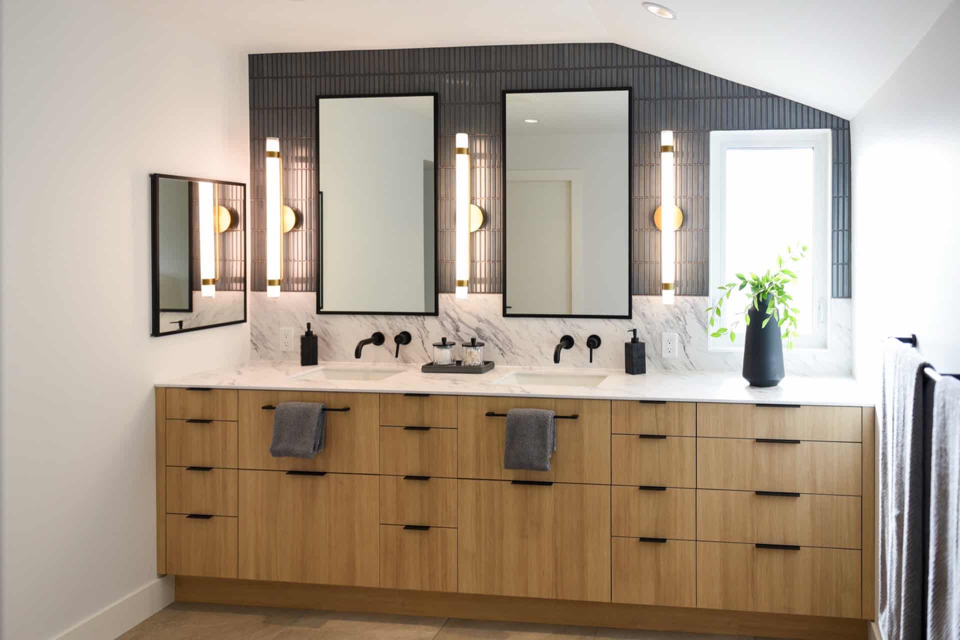 Bright modern bathroom vanity with double mirrors and black fixtures.