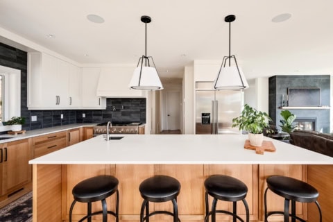 Spacious modern kitchen with large white island and black pendant lights.