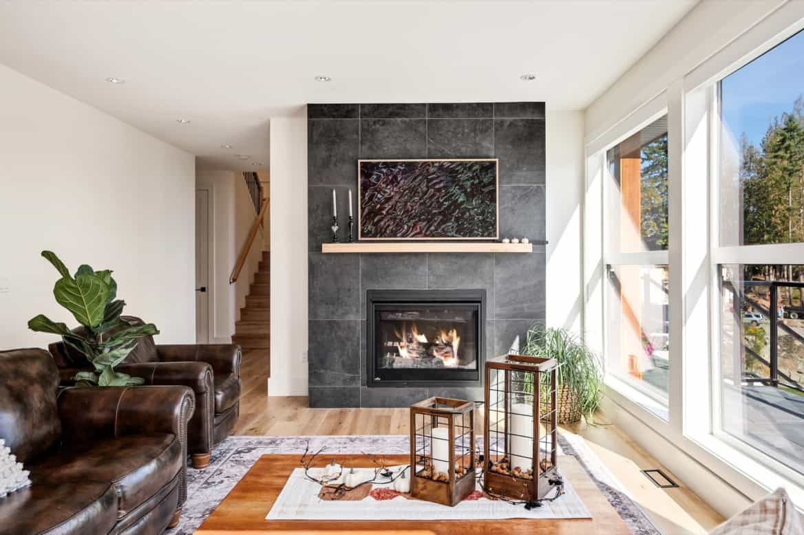 Bright living room featuring a modern fireplace with dark tile surround and large windows.