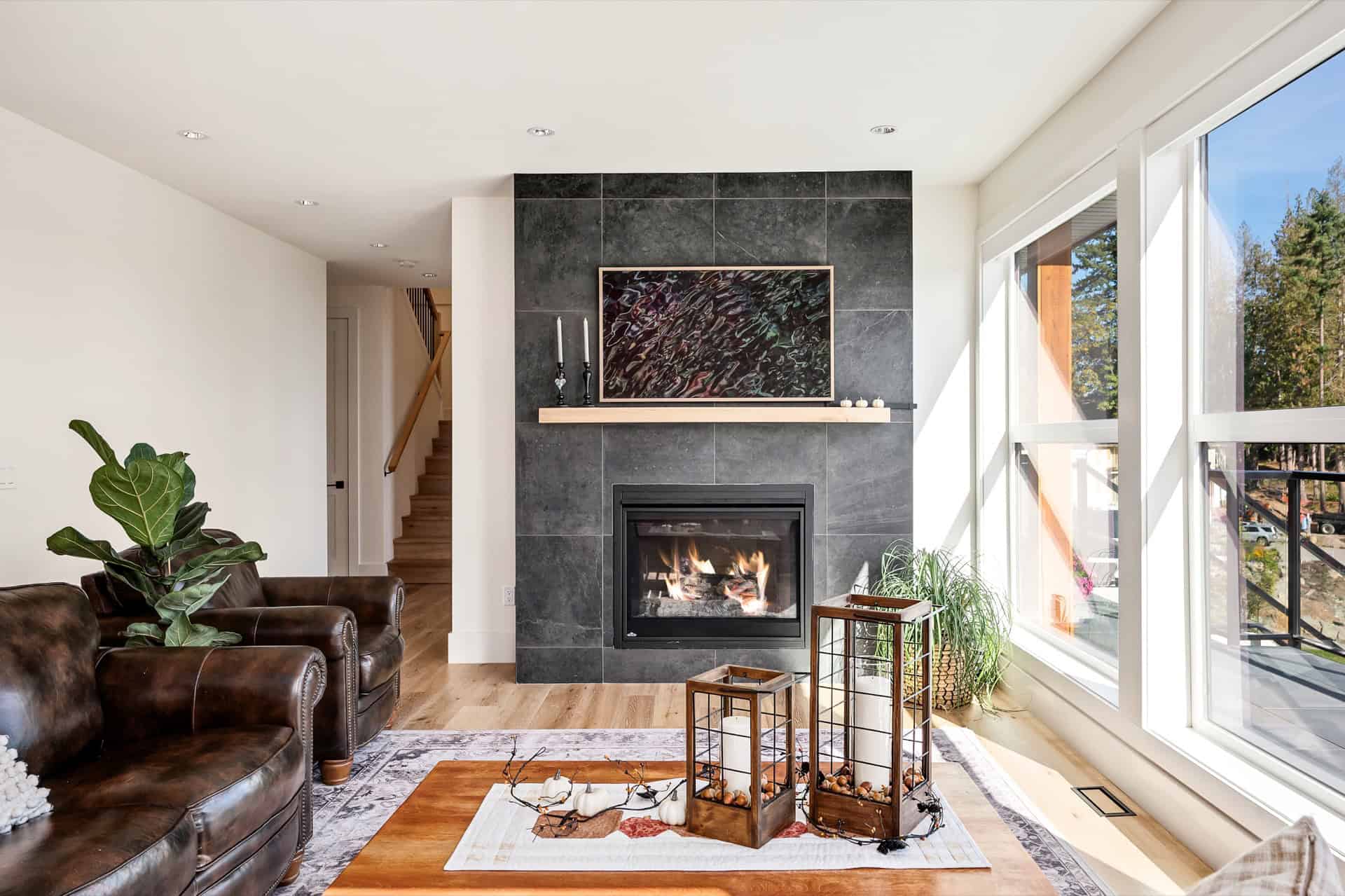 Bright living room featuring a modern fireplace with dark tile surround and large windows.